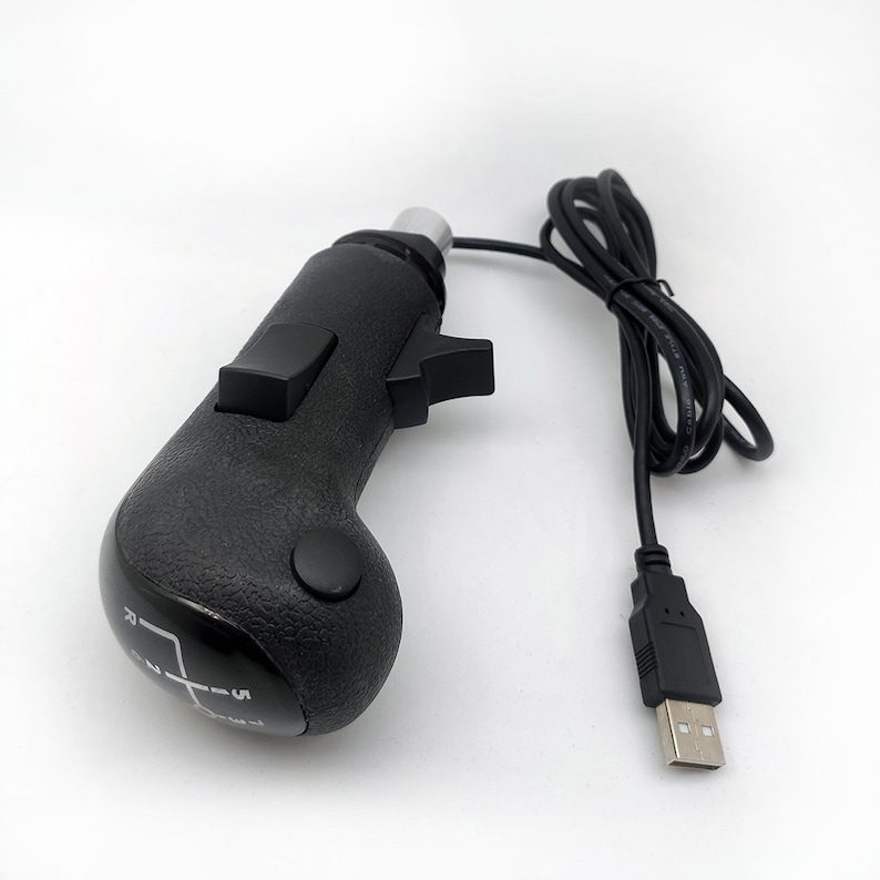 K&ouml;nnte beinhalten: Ein schwarzer, USB-angeschlossener manueller Schalthebel mit einem 5-Gang-Schaltmuster und einem Knopf an der Seite.