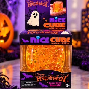 Può includere: Un cubo arancione traslucido e morbido riempito di glitter dorati, confezionato in una scatola nera e viola con l'etichetta Nice Cube Luminous Glitter. La scatola presenta grafiche di Halloween tra cui un fantasma, pipistrelli e il testo Happy Halloween.