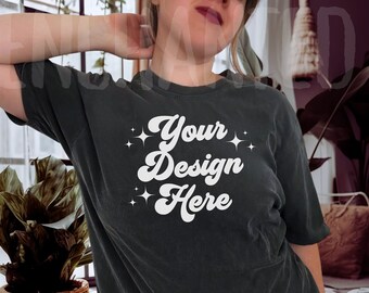 May include: A dark gray t-shirt with a white graphic that says "Your Design Here" with stars on either side of the text. The shirt is being worn by a person with their arm raised behind their head.