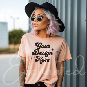 Op de afbeelding: Een perzikkleurig T-shirt met de tekst "Your Design Here" in een retro-lettertype met zwarte glitteraccenten.