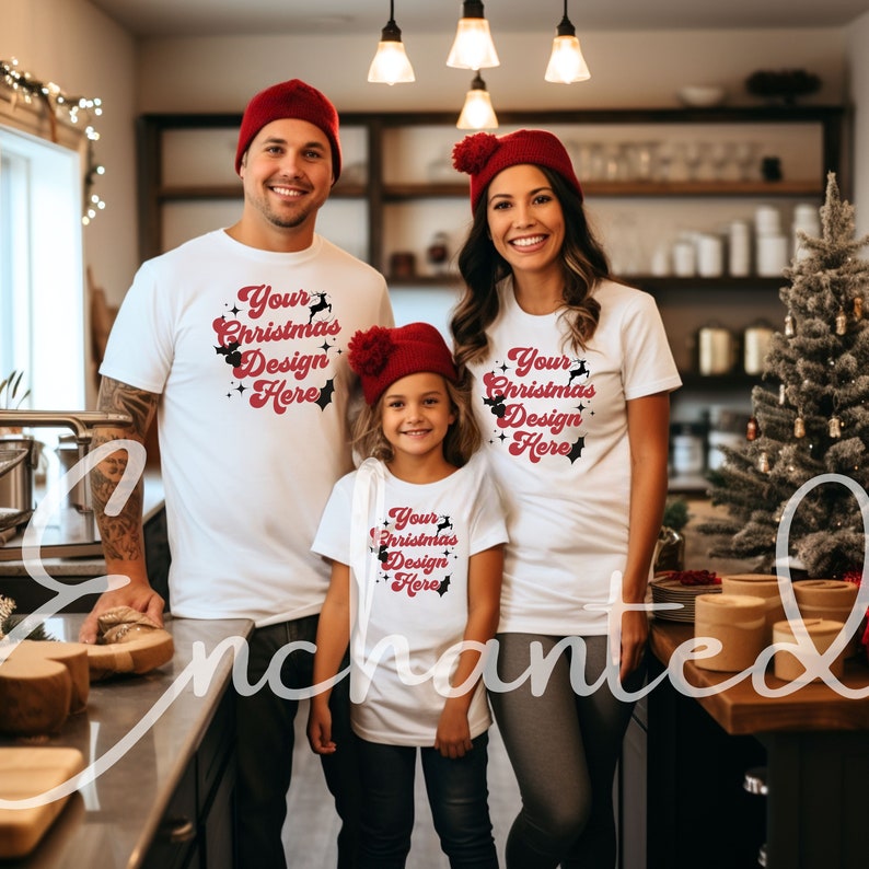 May include: A family of three wearing white t-shirts with a red Christmas design that says "Your Christmas Design Here". The family are standing in a kitchen with a Christmas tree in the background.