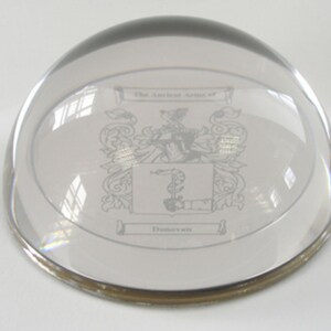 Peut inclure: Un presse-papier en verre transparent avec un bord argent&eacute;. Le presse-papier pr&eacute;sente un blason grav&eacute; avec le texte "The Ancient Arms of Donovan".