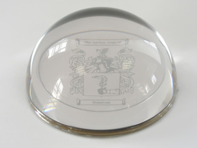 Peut inclure: Un presse-papier en verre transparent avec un bord argent&eacute;. Le presse-papier pr&eacute;sente un blason grav&eacute; avec le texte "The Ancient Arms of Donovan".