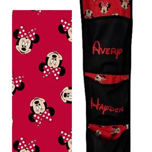 May include: A black and red Minnie Mouse-themed hanging organiser with four pockets. The top section and pocket accents feature a red pattern with Minnie Mouse faces. The pockets are labelled "Avery", "Hayden", and "Livi" in red script.
