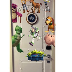 May include: A white door decorated with various Toy Story characters, including Woody, Buzz Lightyear, and Rex. The door also features a circular sign with the number 9652.