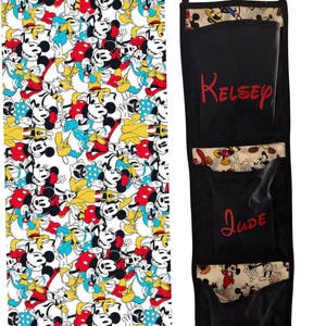 Peut inclure: Tissu avec un motif Mickey Mouse coloré, à côté d'un organisateur noir à trois poches. L'organisateur porte des noms brodés en rouge. Le tissu est étiqueté "Fab 5 Mickey Fish extender fabric."