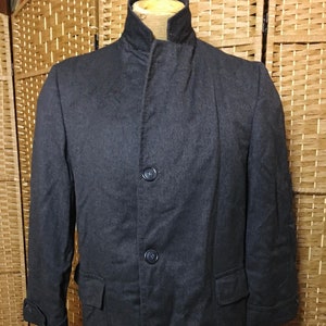 May include: A long, dark gray coat with a stand-up collar and three buttons down the front.