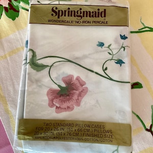May include: Sealed package of Springmaid Wondercale no-iron percale pillowcases. The white fabric features a floral design with pink and blue flowers and green stems. The package states the pillowcases are 20 x 26 inches (51 x 66 cm) and 20 x 30 inches (51 x 76 cm) finished size.