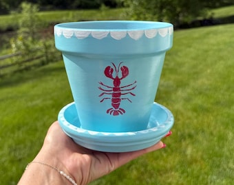 Maceta y platillo con diseño de langosta costera pintados a mano.