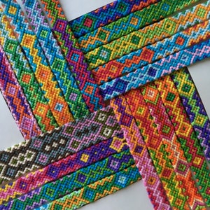 May include: A collection of colorful friendship bracelets woven with different patterns and colors. The bracelets are made with a variety of threads, including pink, blue, green, yellow, orange, and red.