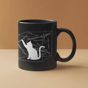 May include: Black ceramic mug featuring a white cat silhouette reaching towards a cube filled with mathematical equations. The mug has a curved handle and is set against a neutral background.