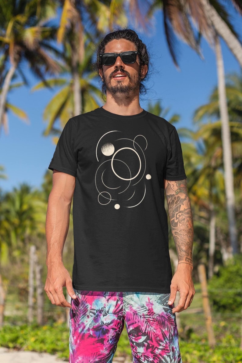 Minimalist geometric t-shirt featuring an elegant beige line art design of interlaced circles and arcs on a black background. The composition evokes motion and balance, creating a modern, artistic look suitable for both men and women.