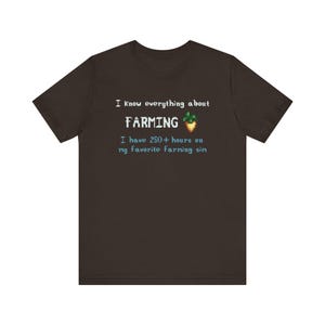 Brown t-shirt with pixelated text reading I know everything about farming followed by a parsnip icon in pixel art, and below it says, I have 250+ hours on Stardew Valley.