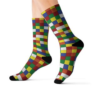 May include: A pair of colorful socks with a geometric pattern. The socks feature a patchwork design of red, green, yellow, blue, and white squares. The heel and toe are black.