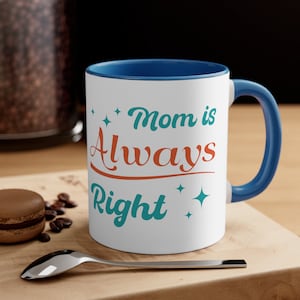 May include: White ceramic coffee mug with a blue rim and handle. The mug has a teal and orange design that says "Mom is Always Right" with stars on either side of the text.