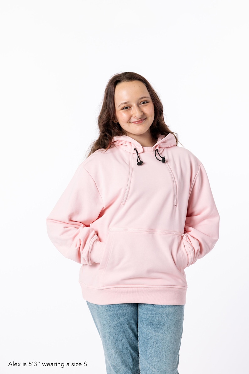 May include: A light pink hoodie with a drawstring hood and a front pocket. The hoodie is made of a soft material and has long sleeves. The model is wearing a size S.