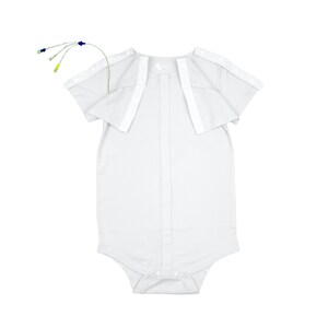 May include: A white baby onesie with short sleeves and a button-down front. The onesie has a snap closure at the bottom and white trim on the shoulders. A small, multi-colored medical device is attached to the top of the onesie.