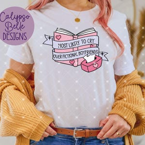 May include: White t-shirt with a pink and black graphic of a book with the text "Most Likely to Cry Over Fictional Boyfriends".