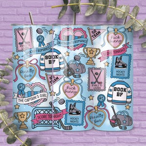 May include: A light blue tumbler with a repeating pattern of hockey-themed illustrations. The design includes hockey sticks, pucks, jerseys, and phrases like "Hockey Romance" and "Score Tonight." The tumbler has a silver straw.