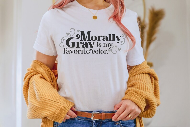 Pu&ograve; includere: Maglietta bianca con il testo "Morally Gray is my favorite color." in lettere nere con cuori e volute grigi.