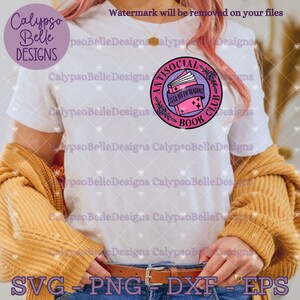 May include: A white t-shirt with a pink and purple circle design. The design features a stack of books with the text "Antisocial Book Club" and "I'd rather be reading".