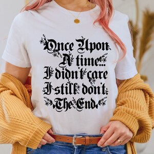 May include: White t-shirt with black text that reads "Once Upon A Time... I didn't care I still don't. The End."