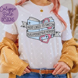 May include: White t-shirt with a graphic of a book with handcuffs and the text "Most Likely to Swoon Over Possessive Heroes".