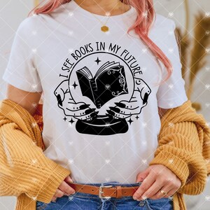 May include: White t-shirt featuring a black and white graphic of a book inside a crystal ball with the text "I see books in my future".