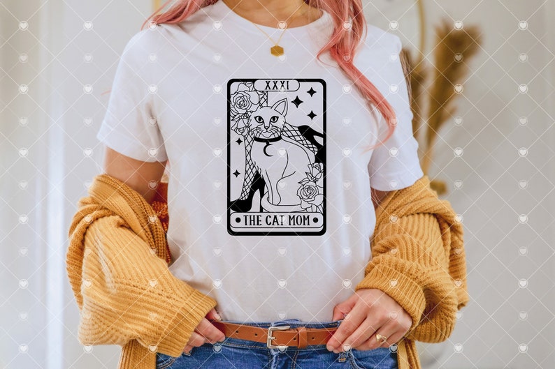 Puede incluir: Camiseta blanca con una ilustraci&oacute;n en blanco y negro de un gato con un collar y sentado en un zapato de tac&oacute;n alto. La ilustraci&oacute;n est&aacute; en el estilo de una carta de tarot y dice "XXXI The Cat Mom".