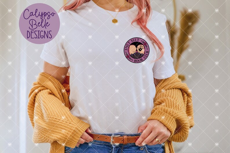 May include: White t-shirt with a purple circle graphic that says "S**LT S**LT BOOK CLUB".