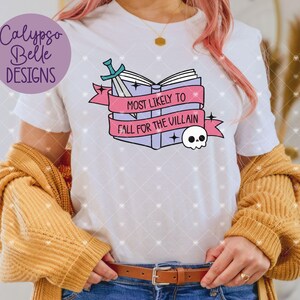 May include: White t-shirt with a pink and blue graphic of a stack of books with a sword and a skull. The text on the graphic reads "Most Likely to Fall for the Villain".
