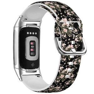 Op de afbeelding: Een zilveren en witte fitness tracker met een zwart band met een bloemenpatroon. Het band heeft een zilveren gesp.