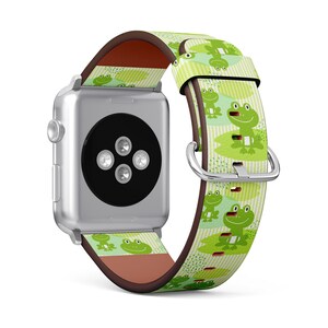 May include: A green and white Apple Watch band with a frog pattern. The band is made of leather and has a brown leather lining.