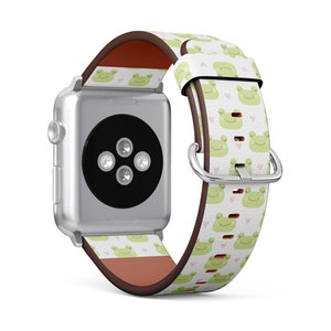 May include: A silver Apple Watch with a white leather band featuring a repeating pattern of green frogs and pink hearts.