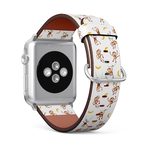 May include: A white Apple Watch band with a brown leather backing. The band features a repeating pattern of monkeys swinging from vines with bananas.