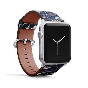 Pode incluir: Um Apple Watch prateado com uma pulseira de couro azul escuro e branco com estampa de tubar&atilde;o. O mostrador do rel&oacute;gio &eacute; preto com ponteiros brancos.