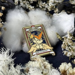Pode incluir: Pin retangular de esmalte com um personagem de desenho animado com detalhes em laranja e amarelo, sobre um fundo azul escuro. O pin tem uma borda dourada e as inscrições "PRIMAL ENERGY" e "PAGE OF WANDS".