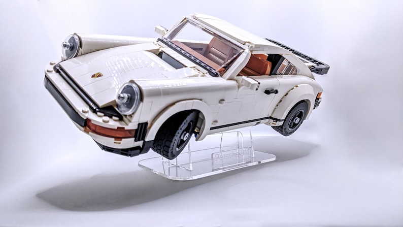 May include: White Lego Porsche 911 Turbo model car on a clear acrylic display stand.