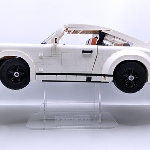 May include: White Lego Porsche 911 Turbo model on a clear acrylic display stand. The car has black wheels and a black rear spoiler.