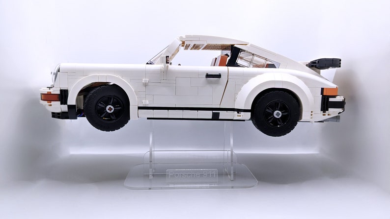 May include: White Lego Porsche 911 Turbo model on a clear acrylic display stand. The car has black wheels and a black rear spoiler.