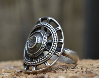May include: A silver ring with a circular design featuring a central dome and concentric circles of raised dots and openwork.