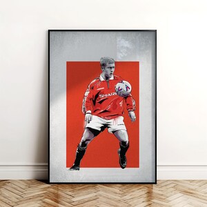 May include: Framed art print of a footballer in a red jersey with "SHARP" on it, white shorts, and black socks, balancing a football. The background is a red and grey gradient. The print is in a black frame.