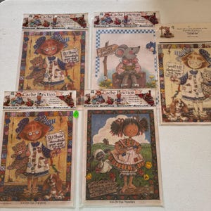 May include: A collection of Cache Junction iron-on dye transfers featuring whimsical illustrations. The transfers depict children with pets, a mouse with luggage, and spring scenes. Each transfer includes text such as "Pet Show" and "Spring has sprung."