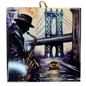 May include: Square canvas art featuring a silhouetted jazz musician playing a saxophone in front of the Manhattan Bridge in New York City. A yellow taxi cab drives down a wet street. The word "NEW YORK" is printed vertically on the right side.