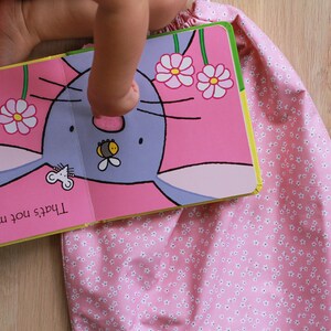 K&ouml;nnte beinhalten: Ein Kinderbuch mit einem rosa Einband und einem Bild eines blauen Hasen mit einer Biene auf der Nase. Der Text auf der Seite lautet "Das ist nicht mein Hase. Seine Nase ist zu flauschig."