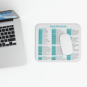 May include: A white mousepad with rounded corners featuring a teal-colored Excel shortcuts guide. The guide includes sections for general shortcuts, formatting, pivot tables, and more. A laptop is partially visible in the upper left corner.