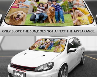May include: A white car with a custom sunshade featuring a collage of family photos. The sunshade has a collage of photos of a family with their dog. The photos are arranged in a grid pattern. The sunshade is installed in the windshield of the car. The car is parked in a parking lot.