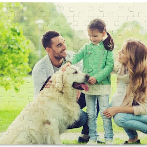 Peut inclure: Une famille de trois personnes, dont une jeune fille, un homme et une femme, profitent d'un moment de d&eacute;tente en plein air avec leur chien golden retriever. La famille sourit et interagit avec le chien dans un parc verdoyant.