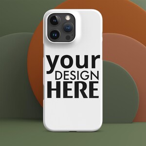 Op de afbeelding: Een witte telefoonhoes met de tekst "your DESIGN HERE" in het zwart. De hoes heeft een uitsparing voor de camera aan de bovenkant. De achtergrond toont abstracte vormen in groen- en oranje tinten.