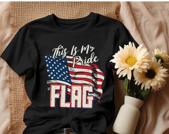 Può includere: T-shirt nero con un design a bandiera americana invecchiata. La bandiera è rossa, bianca e blu, con la scritta "This Is My Pride FLAG" in bianco e rosso. La maglietta è a girocollo e sembra essere di cotone.